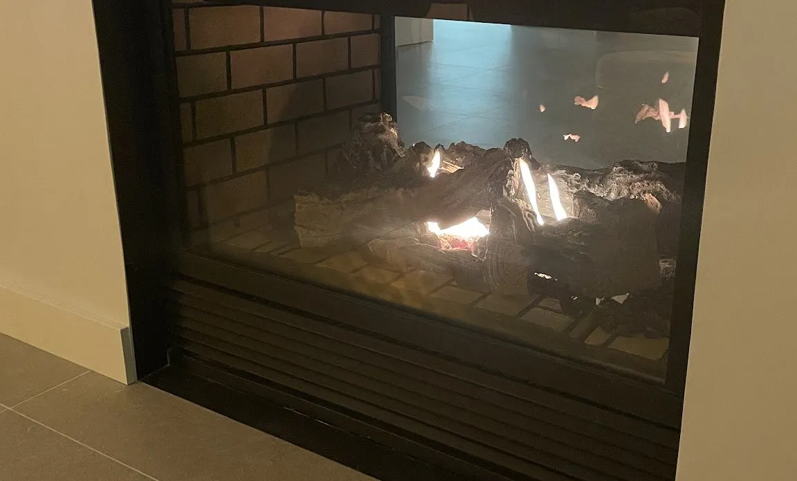 Chimenea de gas de doble cara con troncos encendida, en casa de un cliente