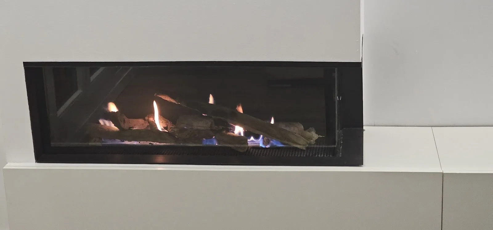 Chimenea de gas en rincón integrada en un mueble blanco, en casa de un cliente