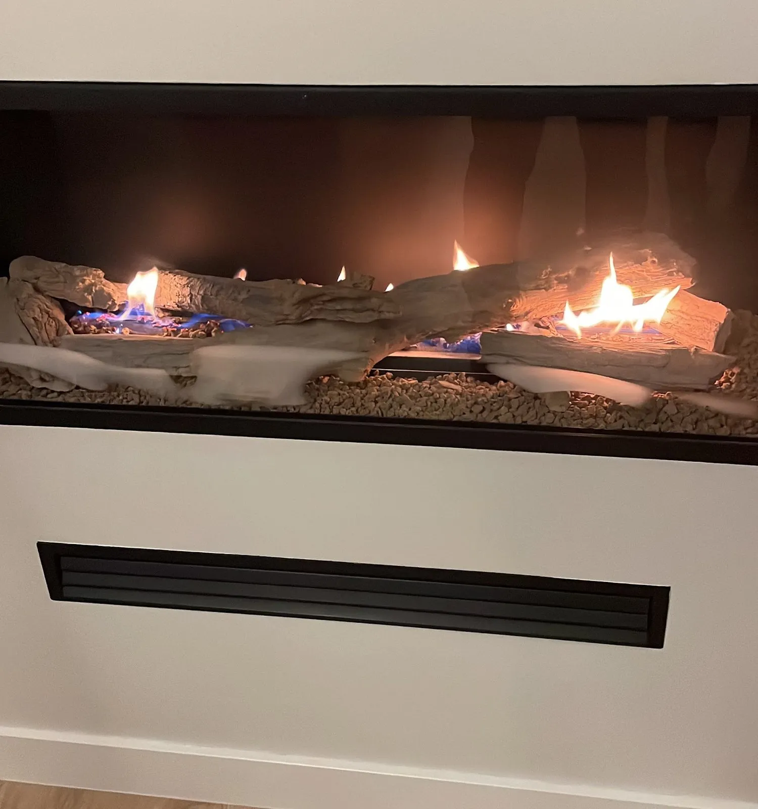 Chimenea de gas a 1 cara con troncos cerámicos y rejilla de ventilación, en casa de un cliente